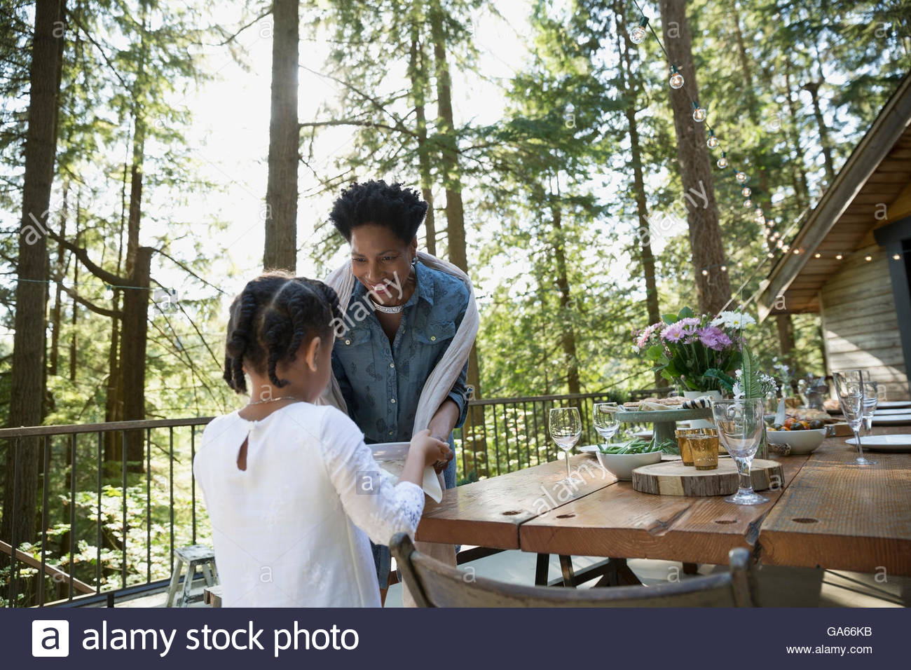 Enkelin hilft Großmutter Dinnerparty auf Kabine Balkon in Wäldern vorbereiten Stockfoto
