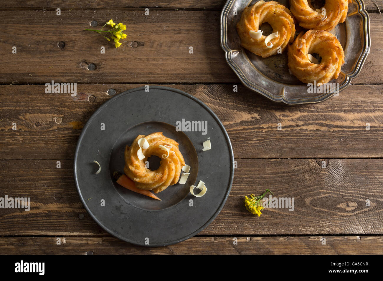Mini-Karotten-Kuchen mit weißer Schokolade auf einem rustikalen Holztisch. Stockfoto