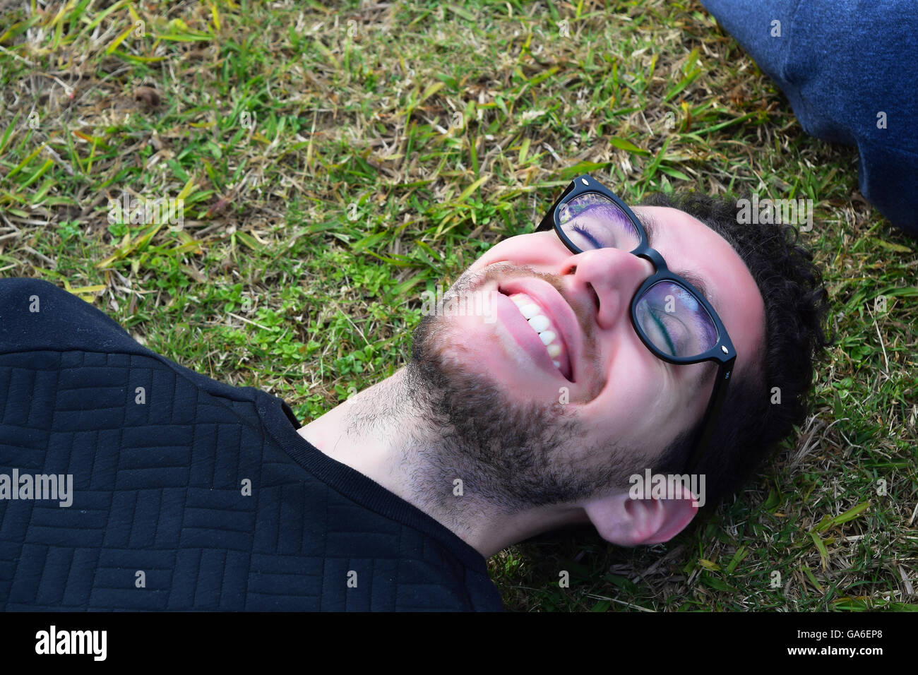 Nahaufnahme des Jünglings Latein entspannend auf dem Rasen. Glücklicher Mann außerhalb ruht. Stockfoto