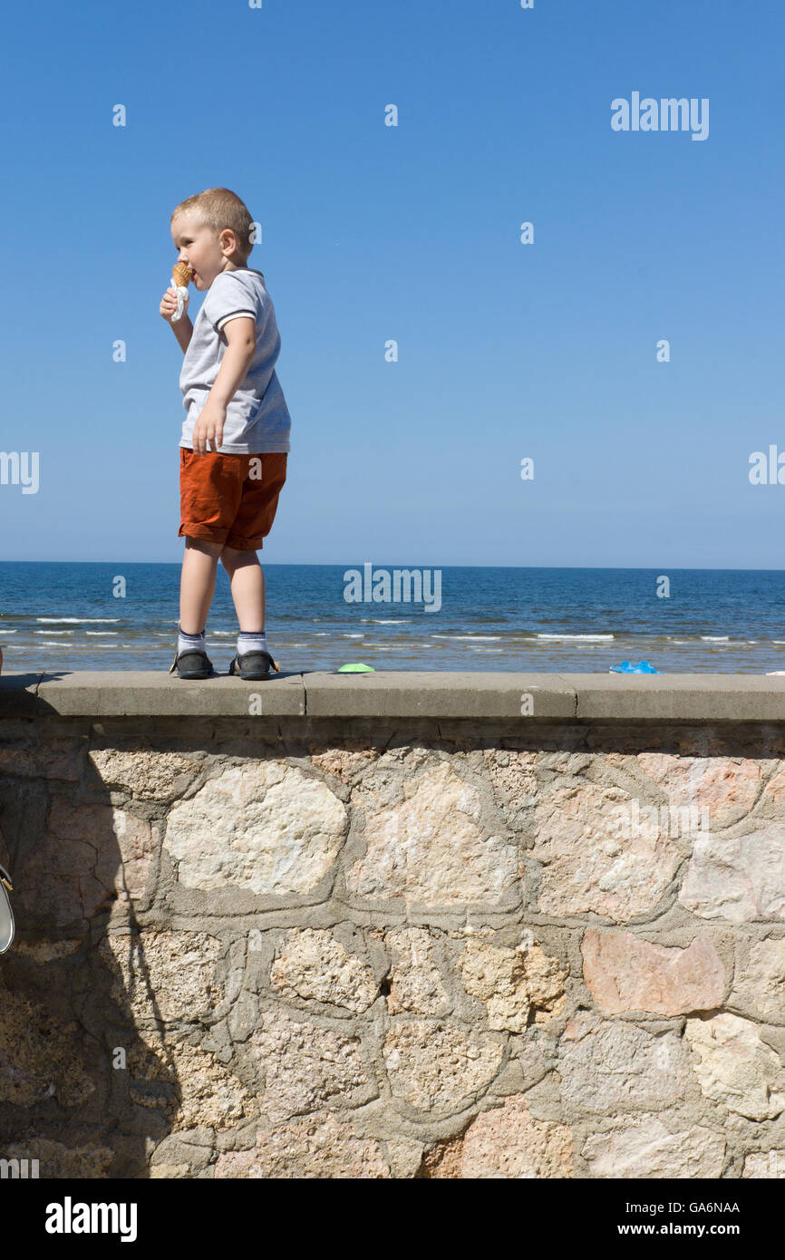 der junge in kurzen Hosen sieht von der Uferstraße am Meer Stockfoto