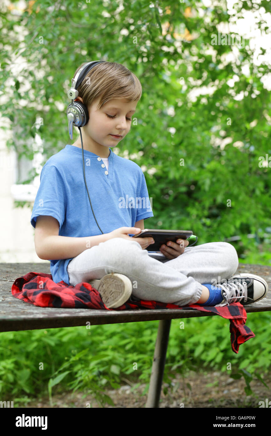 Der junge hört Musik draußen im park Stockfoto