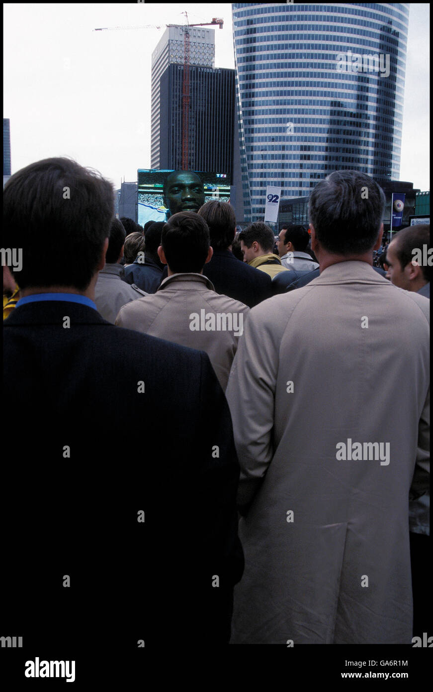 Männer in Regenmäntel beobachten Frankreich Fußball Team spielen in WM auf Großleinwand in La Défense, Frankreich, Juni 2002 Stockfoto