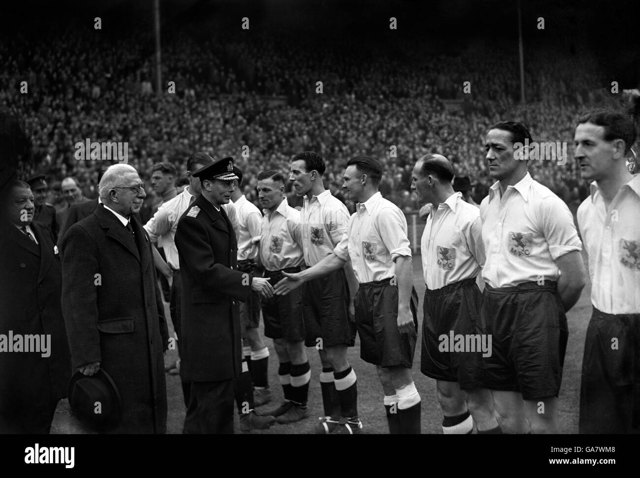 König George VI schüttelt sich die Hände mit Mitgliedern des Millwall-Teams vor dem Auftakt in diesem Krieg Cup-Finale. Stockfoto