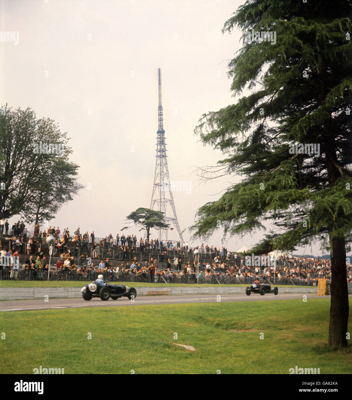 Zwei Veteranen-Rennwagen auf der Geraden auf der Strecke mit den beiden Crystal Palace während einer Kavalkade des Speed für Autos jeden Alters. Im Hintergrund ist der Crystal Palace Fernsehmast Stockfoto
