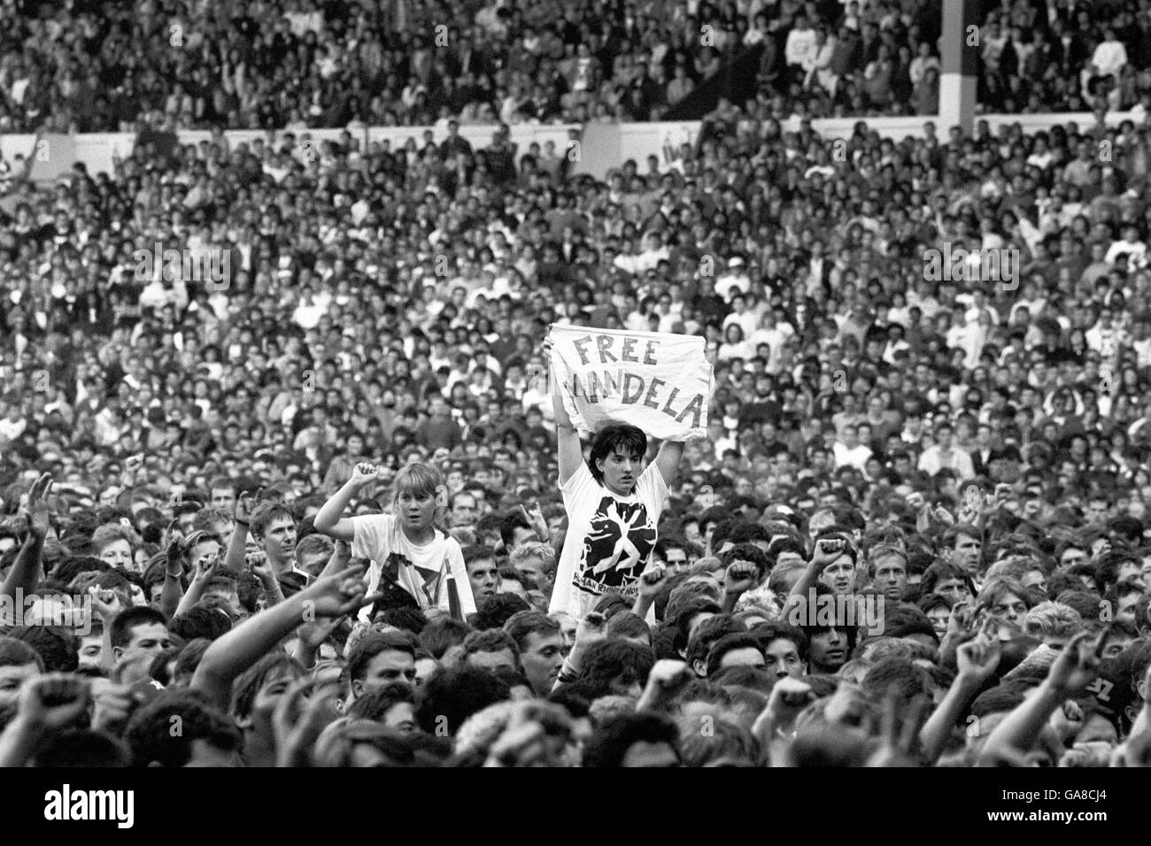 Ein Mitglied der Menge hält ein Banner mit der Aufschrift "Free Mandela" hoch. Hinweis auf Nelson Mandelas Gefangenschaft auf Robben Island Stockfoto
