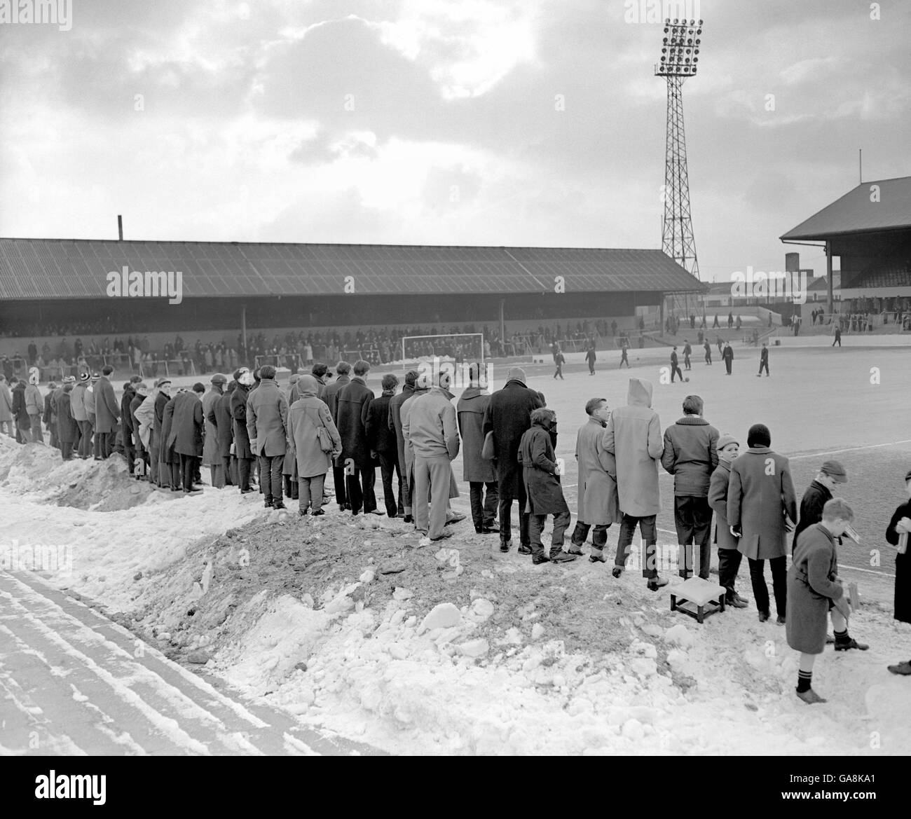 Die Fans von Brighton und Hove Albion beobachten die Spieler, die sich vor dem Spiel von den Schneehüften aufwärmen, die vom Spielfeld geräumt und auf den Terrassen angehäuft wurden Stockfoto