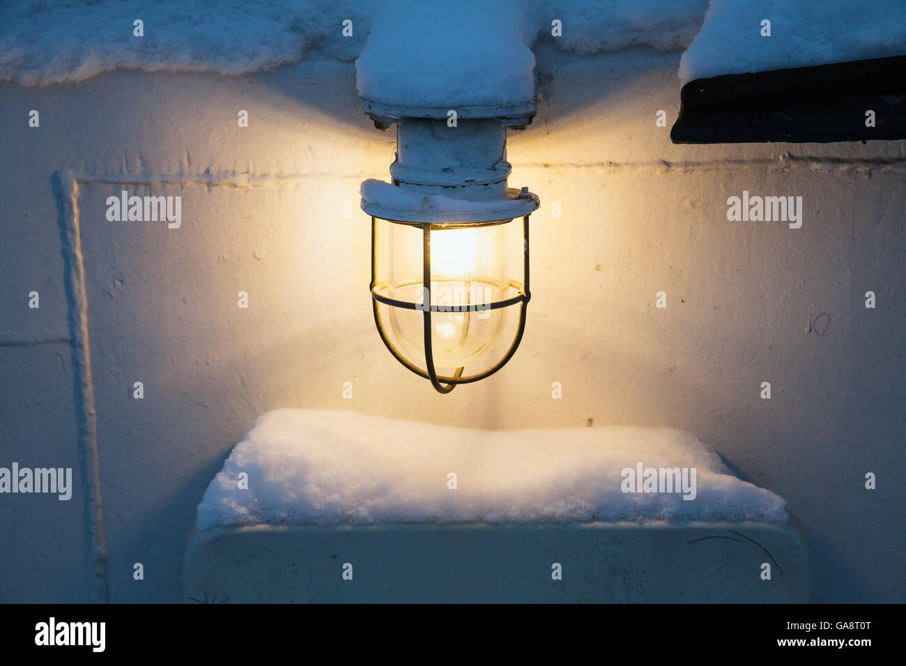 Leuchtende Lampe mit warmem Licht auf weißes Schiff Wand im winter Stockfoto