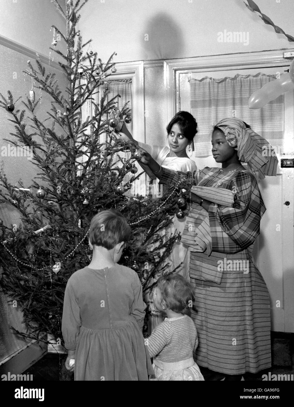 Fatima Chakera (links) aus dar-es-Salaam, Tansania, Studentin am Norwood Technical College und Funlayo Odufuwq aus dem Westen von Nigeria, Studentin am Croydon Technical College, Dekorieren Sie einen Weihnachtsbaum in der Halle des Hauses in der Streatham Road der Familie Norgate. Sie sind zwei der Gruppe von ausländischen Studenten, die Weihnachten mit Bernard Norgate verbringen sollen, einem Exektiv mit einer Smithfield Fleischverpfänkungsfirma, seiner Frau Daphne und ihren teo-Kindern, Deborah, 4, Und Miriam, 16 Monate. Stockfoto