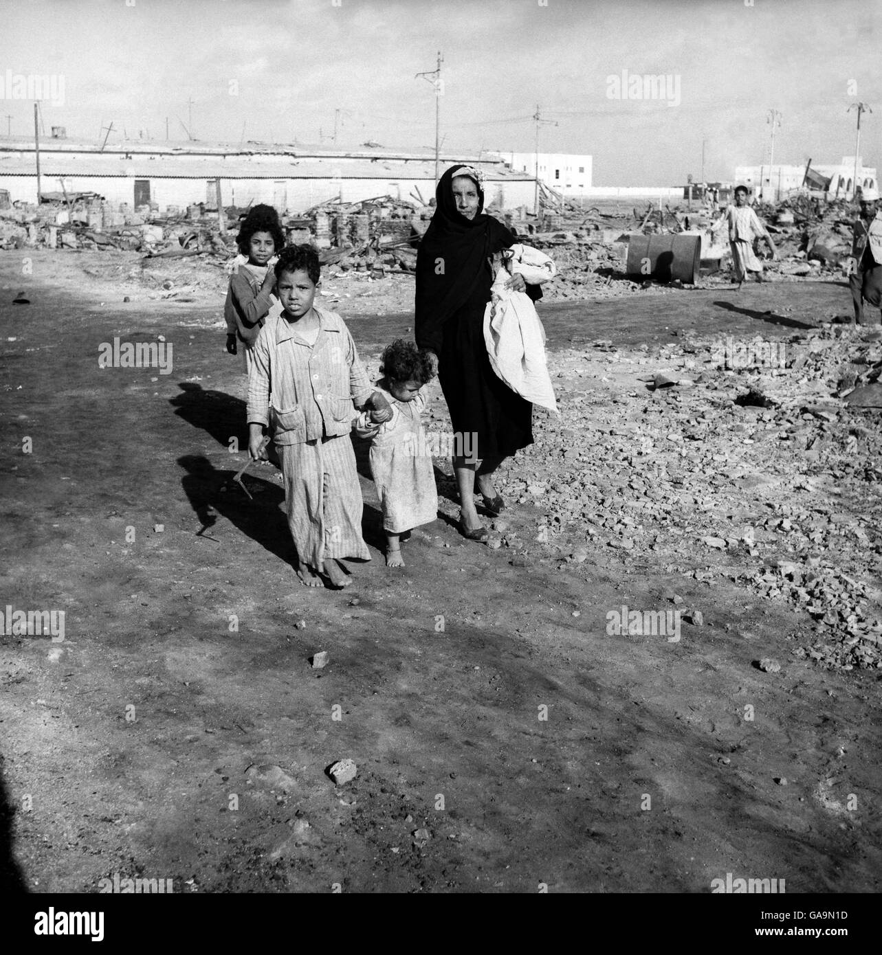 Eine arabische Mutter geht mit ihren Kindern durch die Trümmer Circa 01/01/1956 Stockfoto