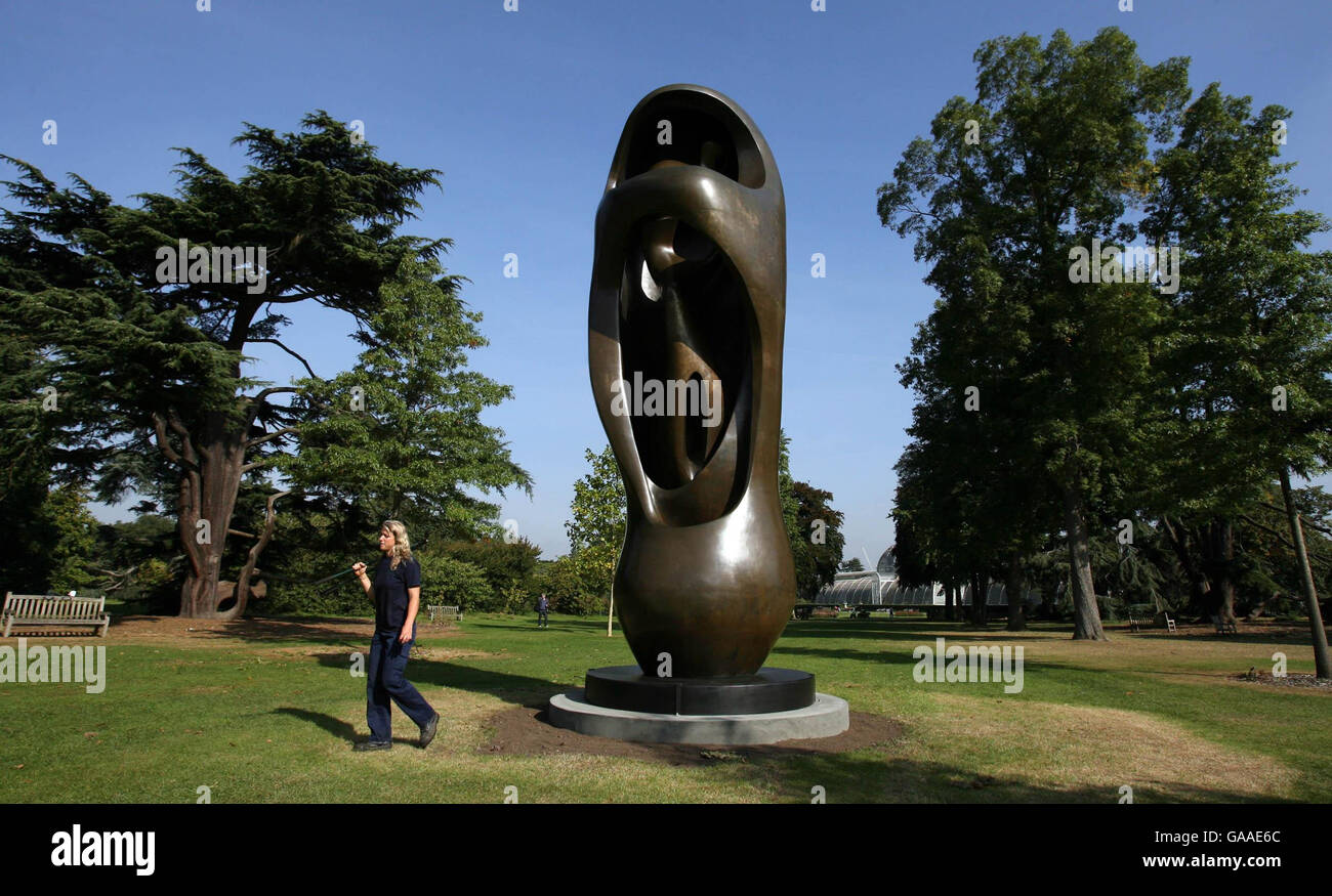 Ein Gärtner kommt an Henry Moores Skulptur namens Large Upright Internal/External Form in Kew Gardens in London vorbei. Stockfoto