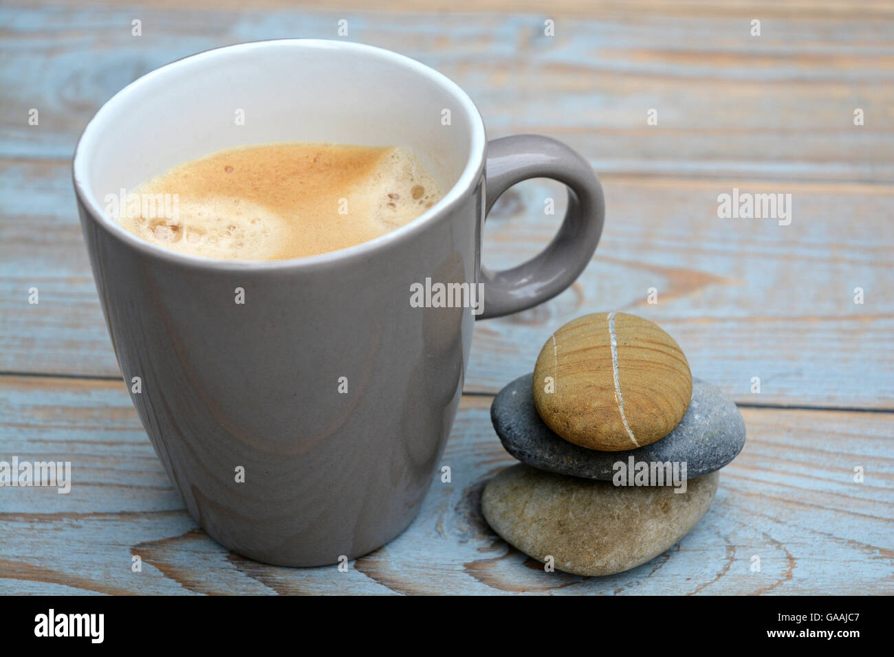 Coffe Cuo auf einem hölzernen Hintergrund mit Zen Crain Steinen Stockfoto