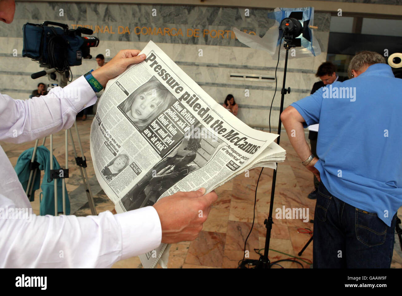 Ein Journalist liest eine britische Zeitung und berichtet über den Fall des vermissten Mädchens Madeleine McCann vor dem Gericht in Portimao, Portugal, wo der Staatsanwalt Kisten mit Akten über den Fall des vermissten Vierjährigen erhalten hat. Stockfoto