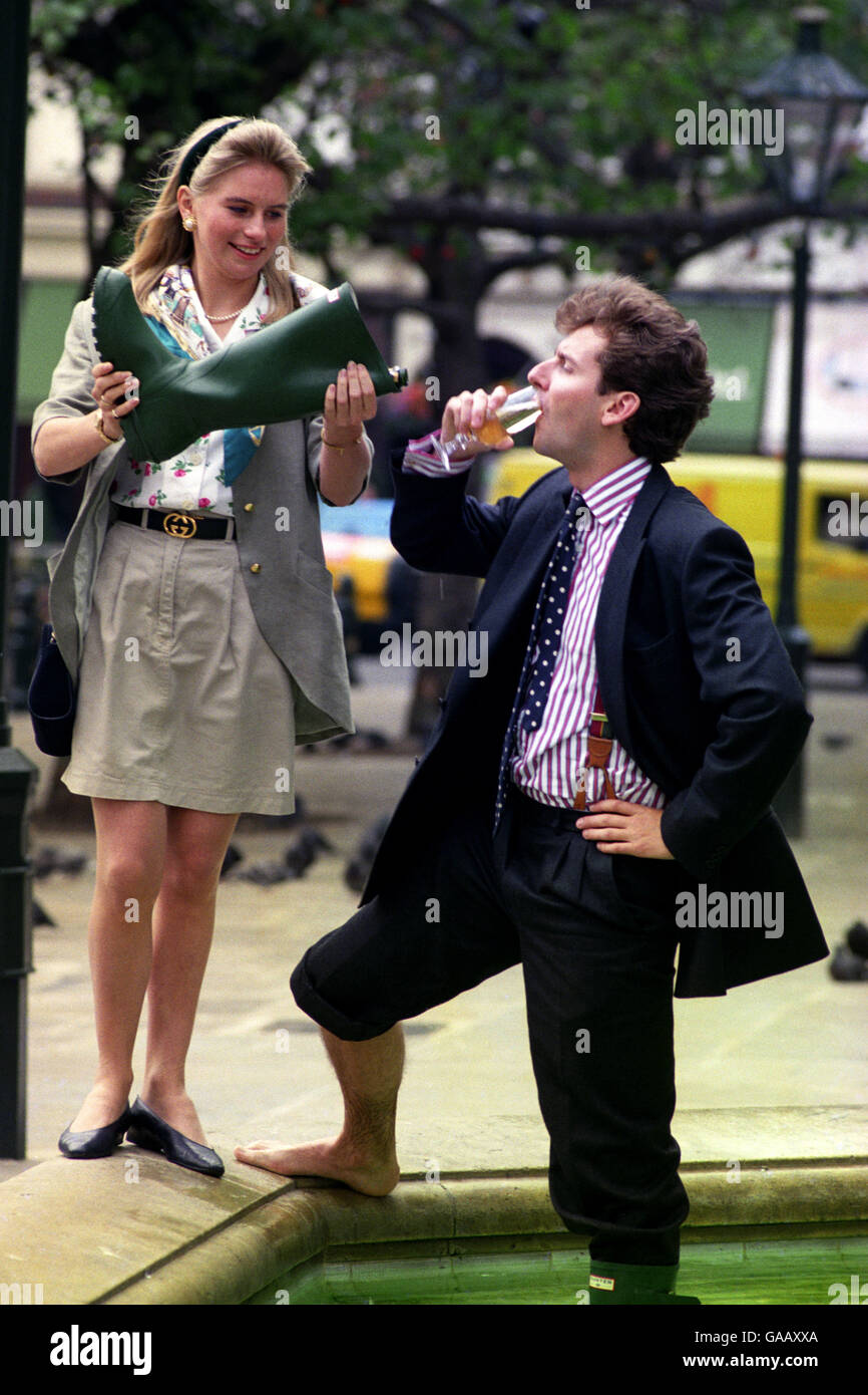 Der Versicherungsmakler Rupert Murray, 26, feiert seine Auswahl als Harper und Queen Sloane Ranger des Jahres 1991 mit Champagner aus einem grünen Gummistiefel, der heute von seiner Freundin Becky Bones im Sloane Square, London, gegossen wird Stockfoto