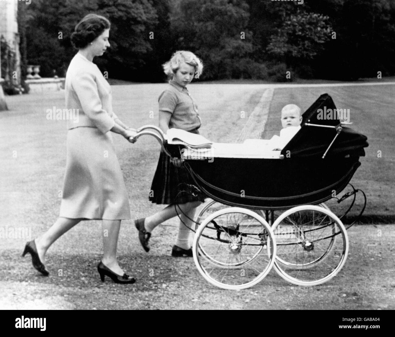 Die Königin, begleitet von Prinzessin Anne, schiebt den Kinderwagen ihres jüngeren Sohnes, Prinz Andrew, während eines Spaziergangs auf dem Gelände von Balmoral. Stockfoto