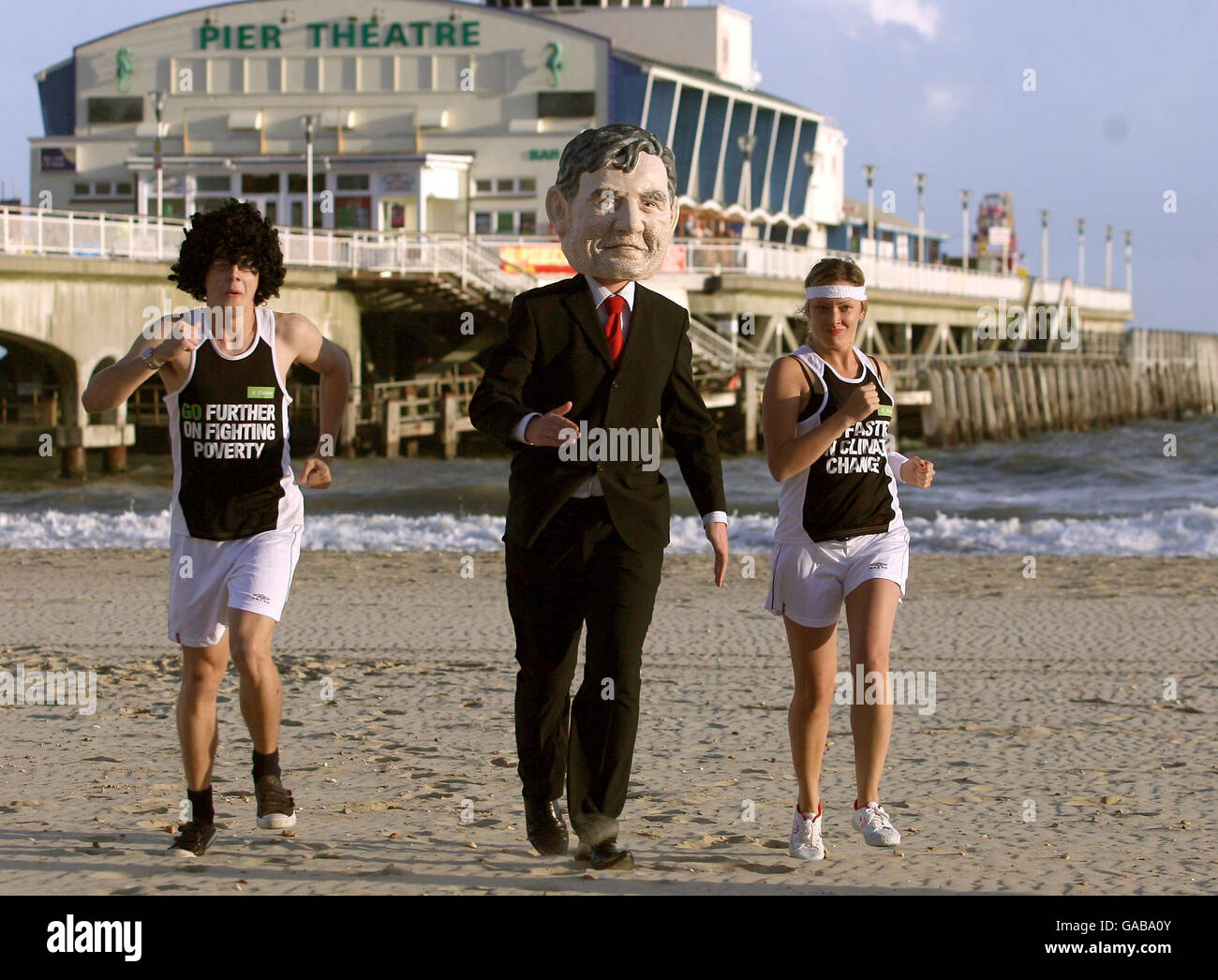 Oxfam-Aktivisten tragen Laufausrüstung und kleiden sich als Premierminister Gordon Brown am Bournemouth Beach, Dorset. Stockfoto