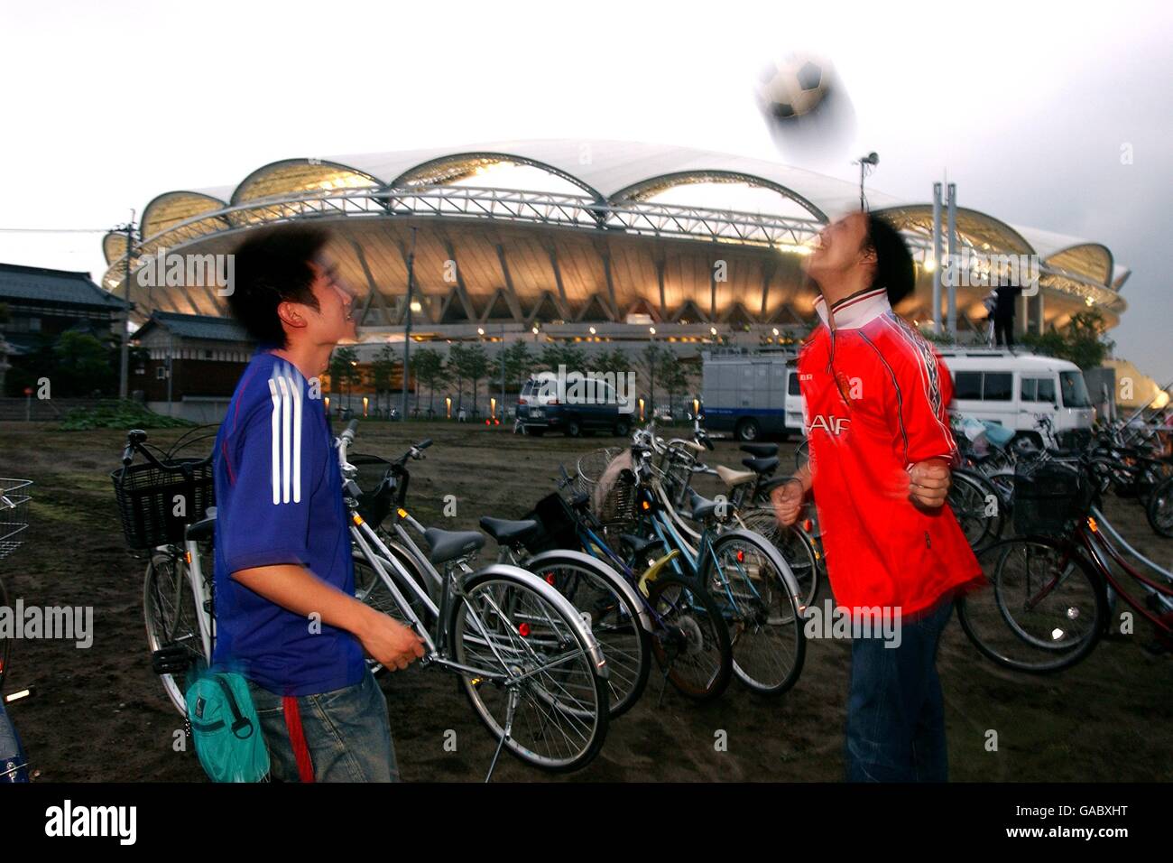 Zwei japanische Fußballfans in einer japanischen Nationalmannschaft shirt und Manchester United Shirt spielen Kopf Tennis außerhalb der Big Swan Stadium in Niigata Stockfoto