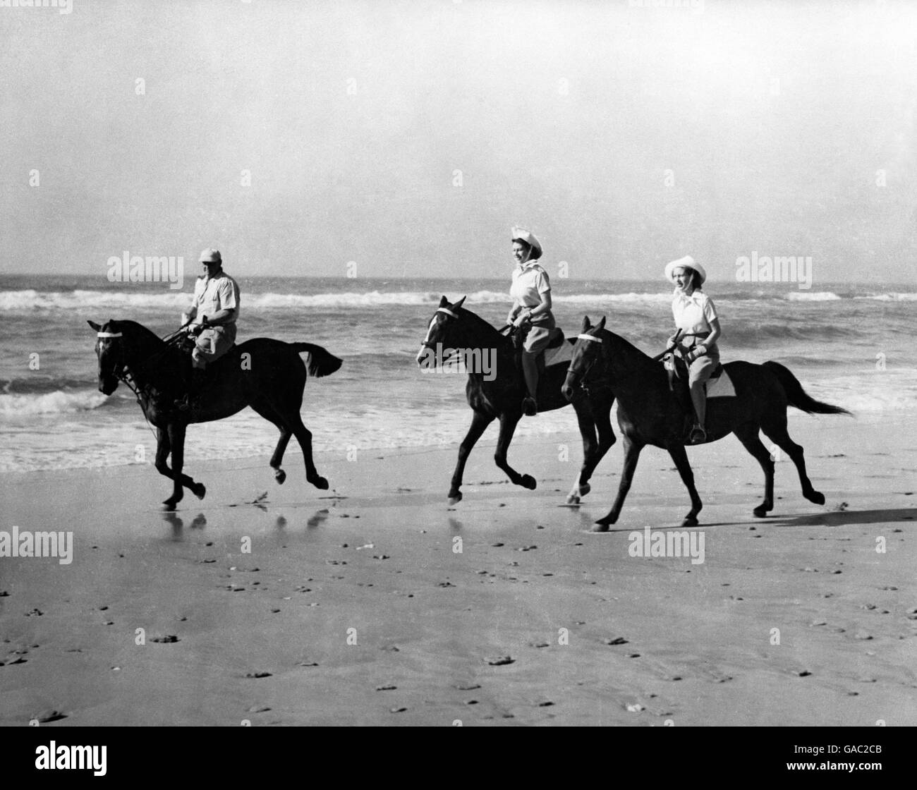 Die Prinzessinnen genossen eine Auszeit von der königlichen Tour durch Südafrika, als sie auf dem goldenen Sand von Bonza Beach, East London, reiten, Prinzessin Elizabeth (Mitte) reitet auf Yvonne Hayhoes 'Jill', während Prinzessin Margaret auf dem 'Treasure' von Pat O'Reilly aus East London reitet, Wer wird gesehen, wie er die Prinzessinnen eskortiert. Stockfoto