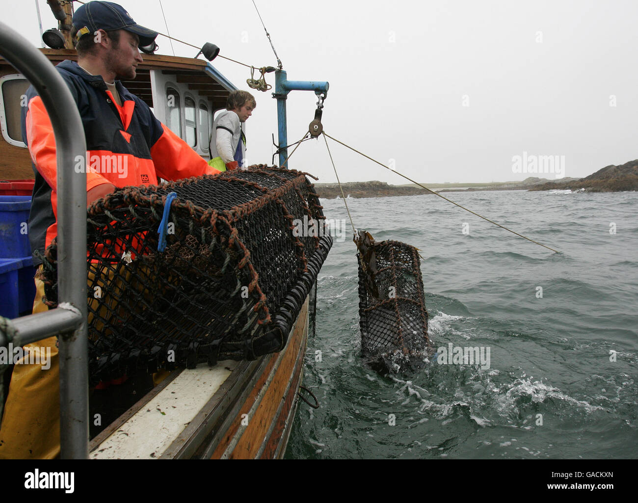 Hummer Fisherman Ross MacLennon Skipper des 'Carrie Anne' Bootes Von Milton Harbour auf der Isle of Tiree mit Deckhand William Walker (trägt Hut) Land Hummer im Atlantik Stockfoto