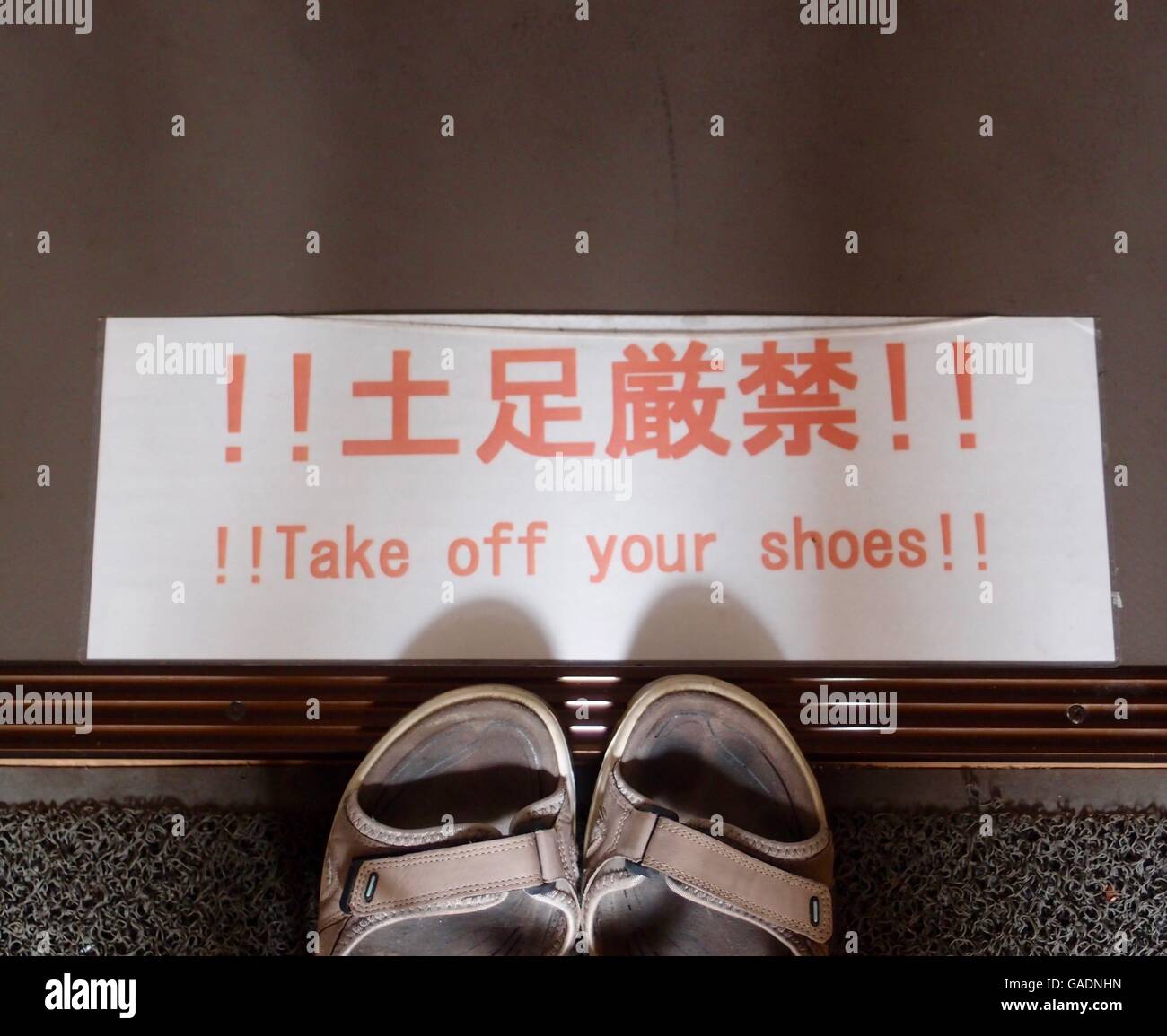 Typische japanische Zeichen auf dem Boden, in Japanisch und Englisch: "Zieh  deine Schuhe aus!" Die Zehen ein paar Sandalen darunter Stockfotografie -  Alamy