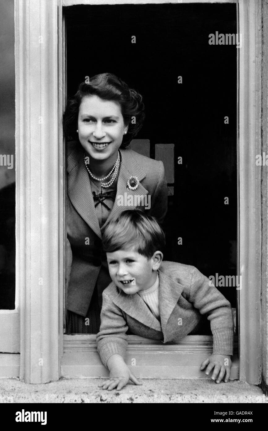 Prinz Charles blickt an seinem vierten Geburtstag nach draußen, während er sich mit seiner freundlich lächelnden jungen Mutter, der Königin, aus einem Fenster lehnt. Stockfoto