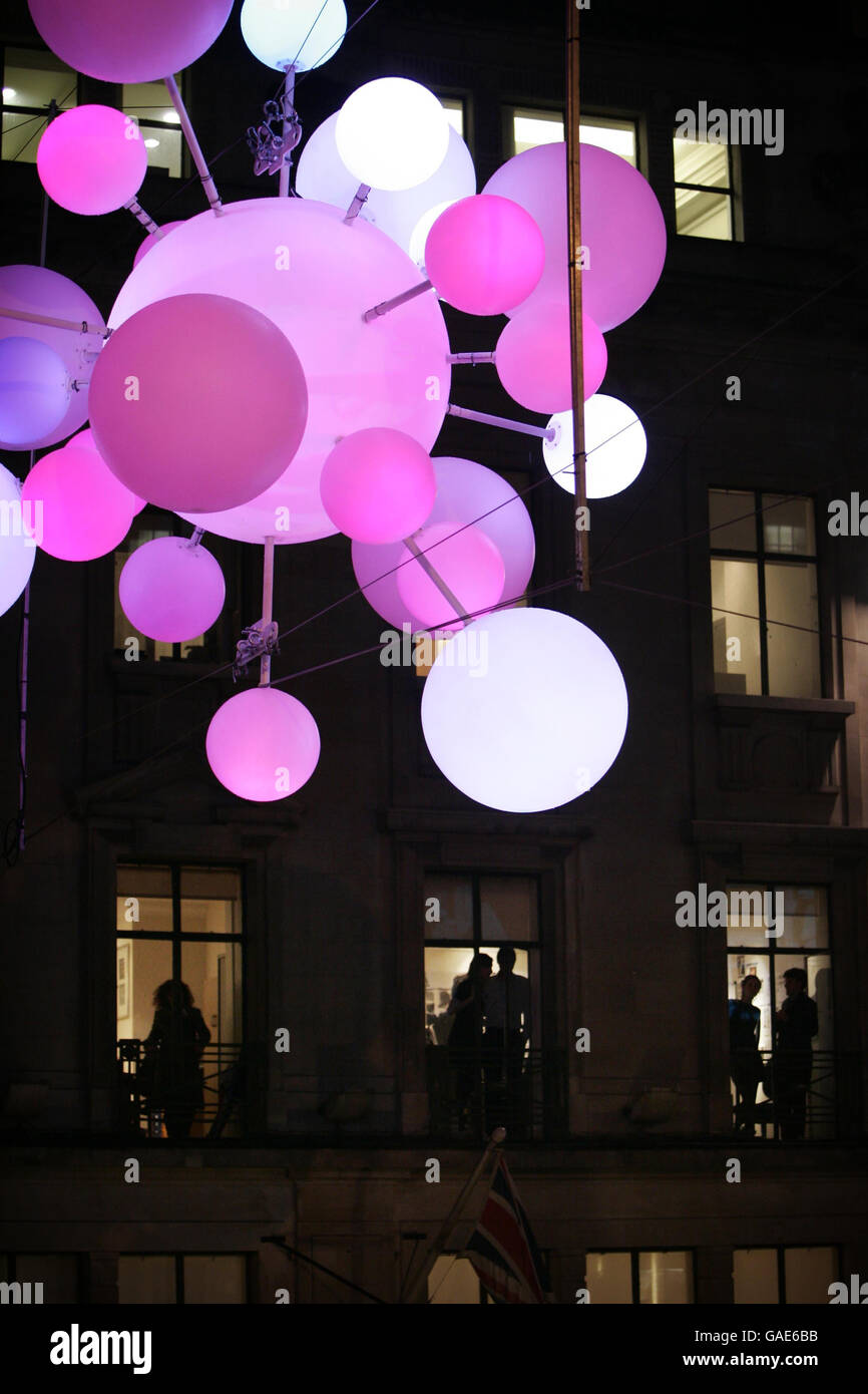 Die Arbeiter beobachten aus ihren Fenstern, wie die Weihnachtsbeleuchtung in der Regent Street, London, eingeschaltet wird. In diesem Jahr waren die Lichter inaktiv, sie wurden eingeschaltet, während die Leute unter ihnen gingen. Stockfoto