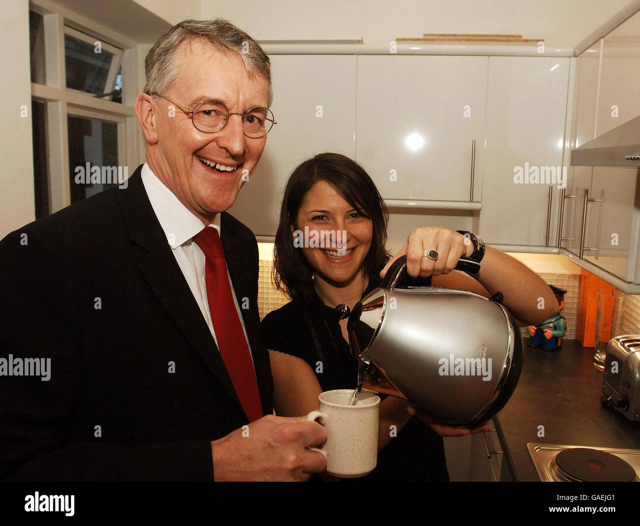 Umweltministerin Hilary Benn hält einen Kaffeebecher in der Hand, als Jo Bloom ihren energiesparenden Wasserkocher in ihrer neu renovierten Umbauwohnung im Norden Londons nutzt. Stockfoto