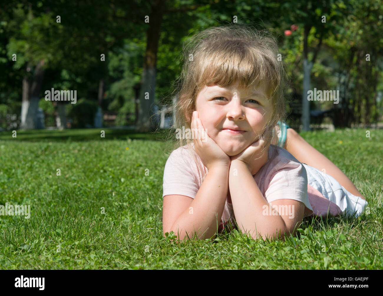 fröhliches kleines Mädchen ins frische Gras liegend Stockfoto