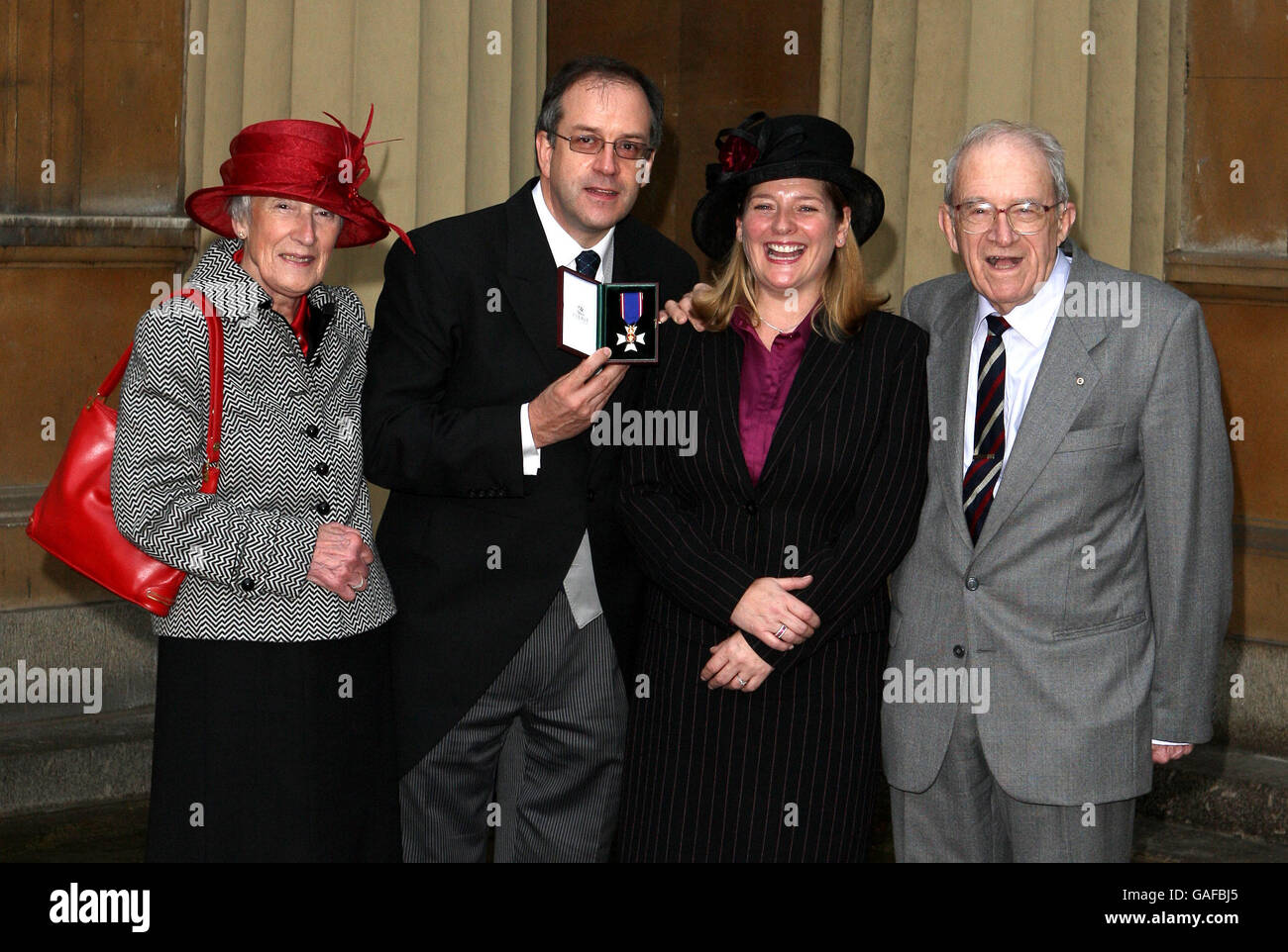 Martin Keene (C), Gruppenbildredakteur der Pressevereinigung, sammelt mit Mama Pamela Keene (L), Verlobter Laura Kerr und Vater John Keene seinen Royal Victorian Order Stockfoto