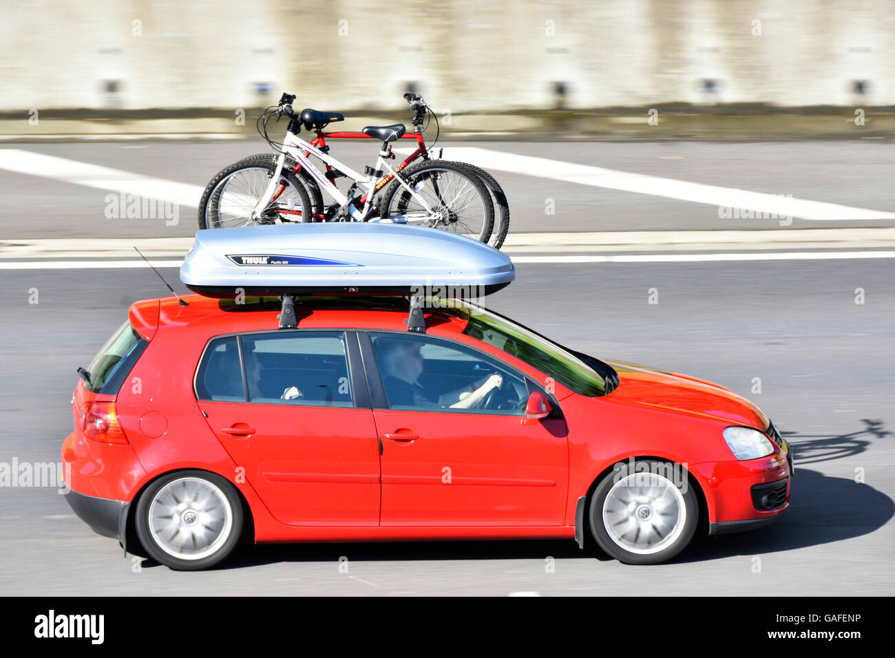 Rote Auto & Fahrer fahren UK Autobahn mit Box und Fahrrad Dachträger geladen mit Herren und Damen Fahrrad für den Radsport Pause Stockfoto