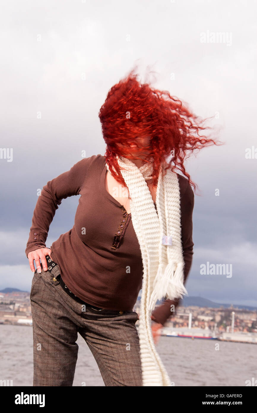 Eine Frau, die entlang der Küste des Firth of Tay an einem sehr windigen Tag mit ihrem Haar in die Luft gesprengt durch den Wind in Fife, UK Stockfoto