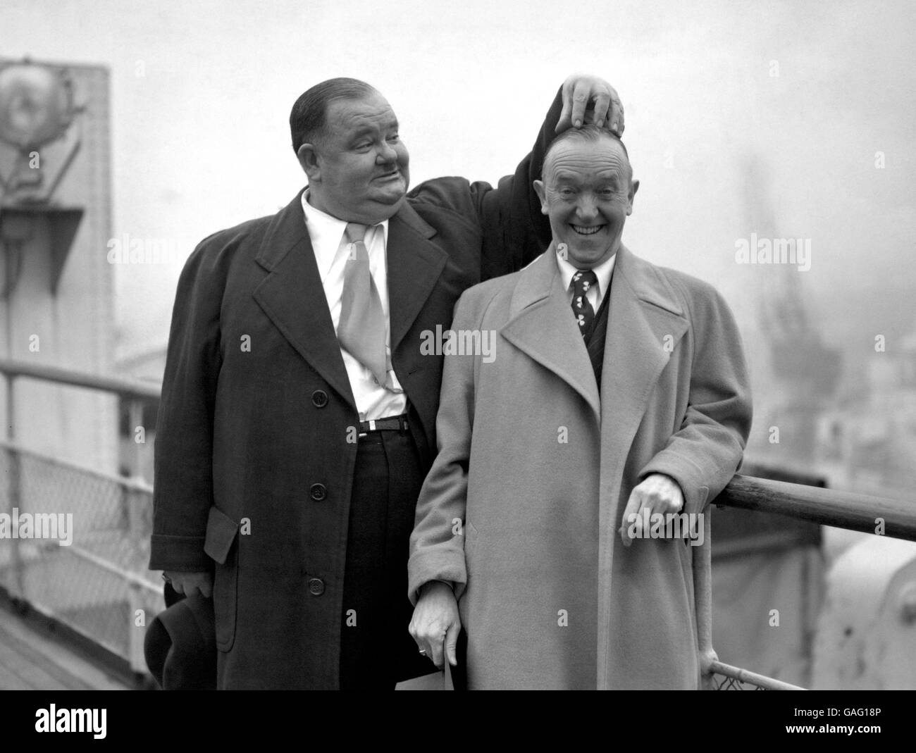 Oliver Hardy kratzt sich am Kopf von Stan Laurel, während das berühmte Paar auf der 'Queen Elizabeth' in Southampton posiert. Es ist ihr erster Besuch im Land seit 1932. Stockfoto