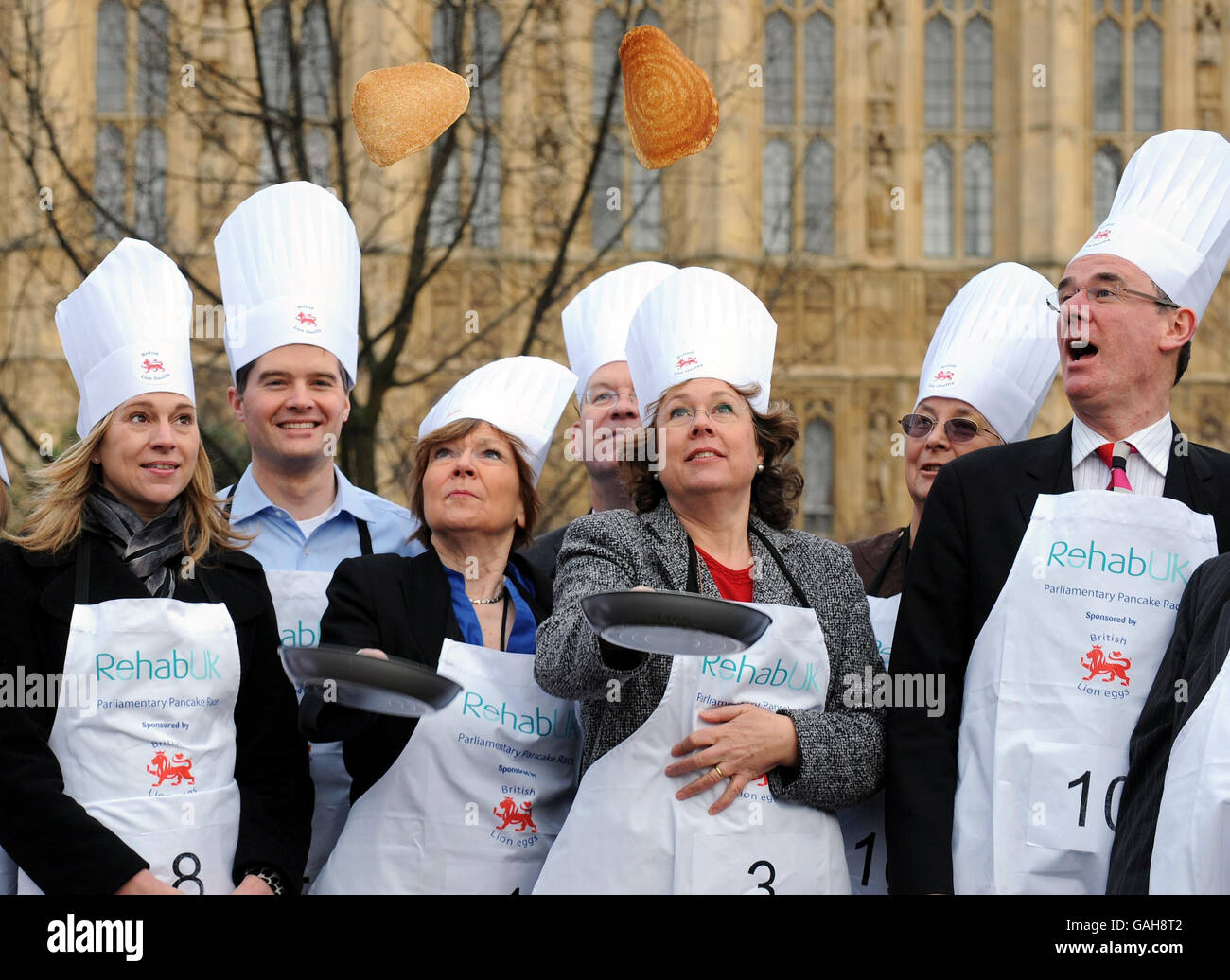 Baroness Garden of Frognal, Linke, und Baroness Northover üben ihren Pfannkuchen vor dem Houses of Parliament, London, zu werfen, bevor sie am Parliamentary Pancake Race teilnehmen. Stockfoto