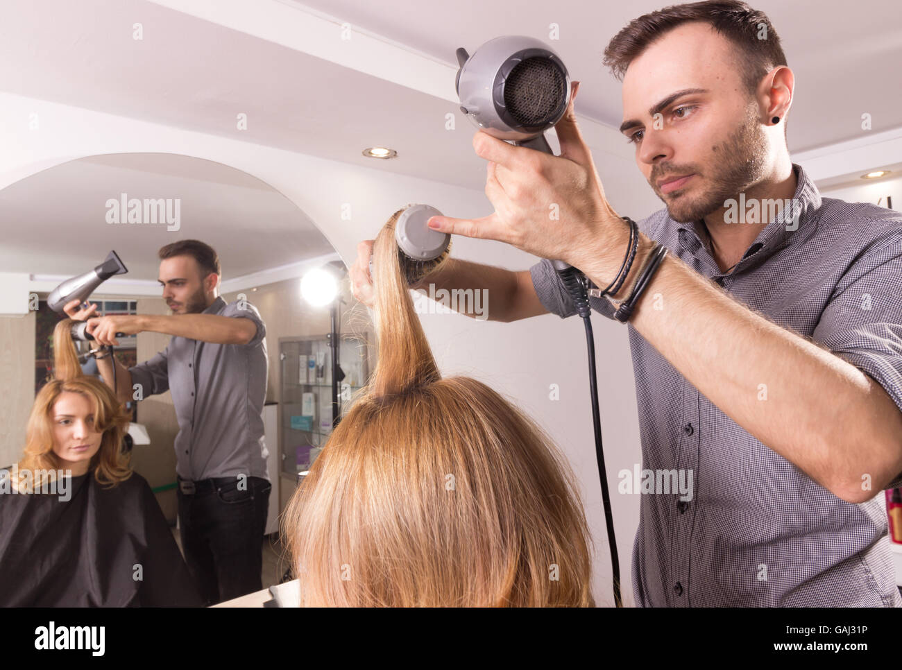 Mann Friseur Föhnen Kamm Walze Haar der Frau, Sicht nach hinten. Stockfoto