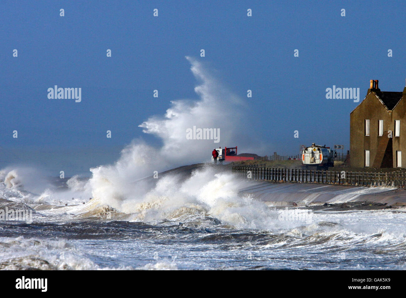 Eine Welle bricht über die A956 zwischen Allonby und Silloth in Cumbria, wenn das schlechte Wetter anhält. Stockfoto