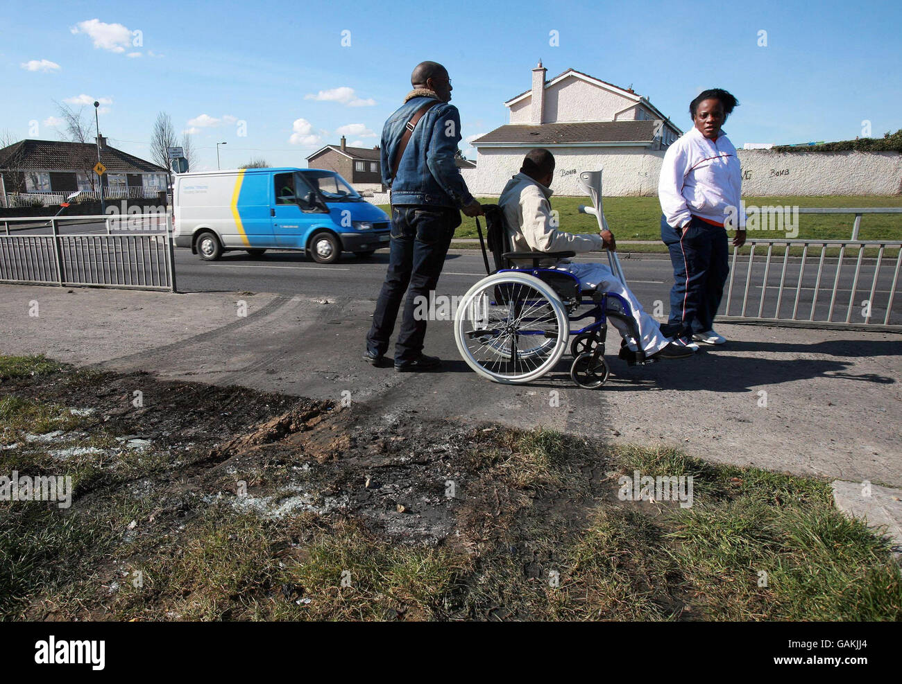 Eine eingewanderte Familie aus dem Kongo schaut auf eine Lücke in einem Geländer, die durch ein Auto verursacht wird, das durch einen Zaun gefahren und in Dublin angezündet wird. Stockfoto