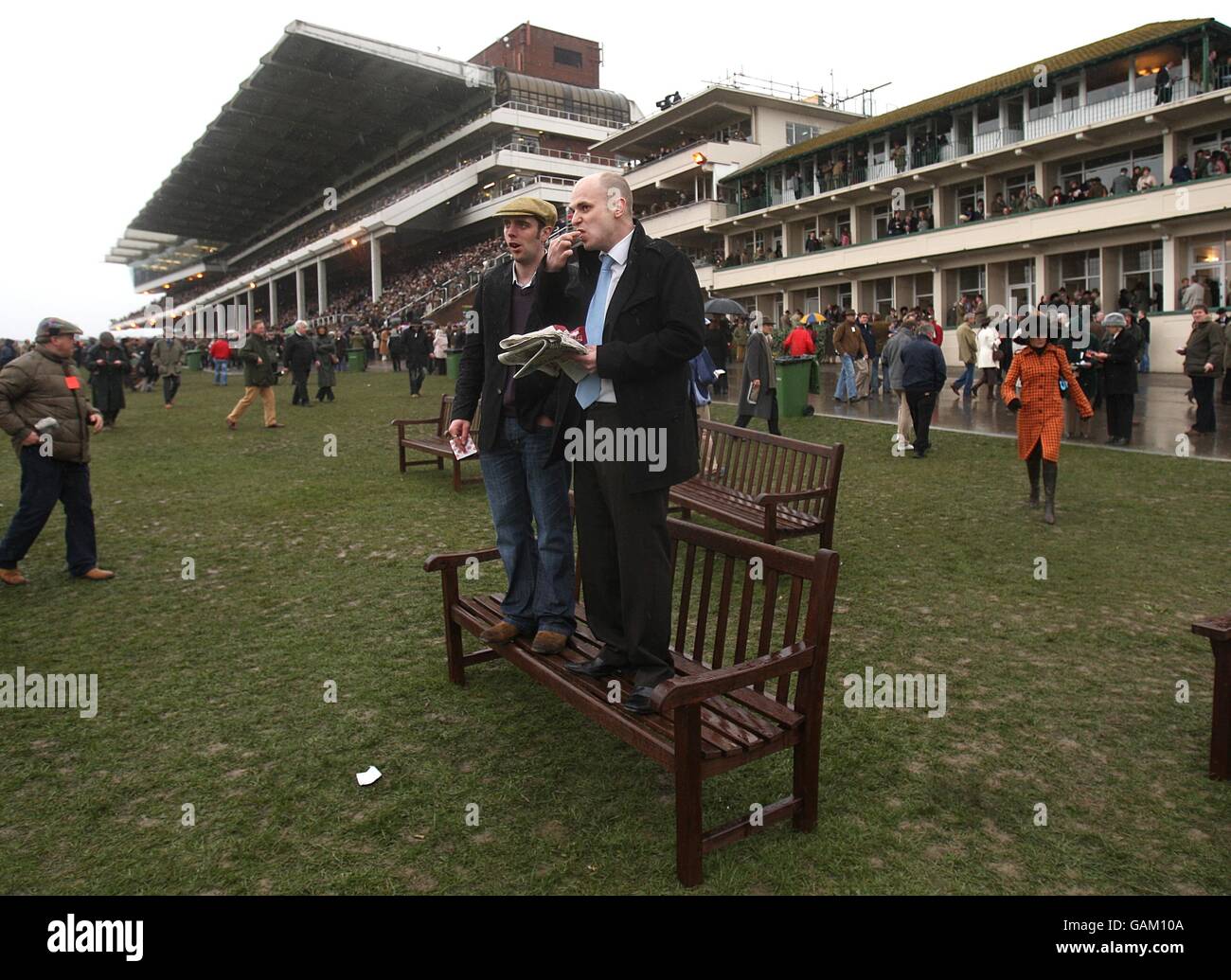 Pferderennen - Cheltenham Festival - Tag Drei - Cheltenham Rennbahn. Die Punter beim Cheltenham Festival halten ihre Füße trocken, während sie auf das nächste Rennen warten Stockfoto