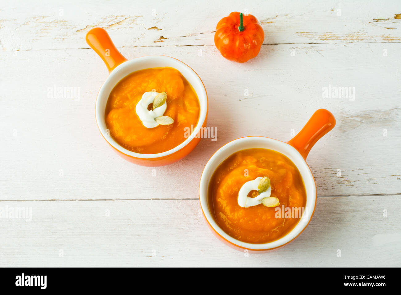 Kürbis squash Gemüsesuppe mit Sahne in einem Teller Kokotten, orange mit Griff, Ansicht von oben Stockfoto