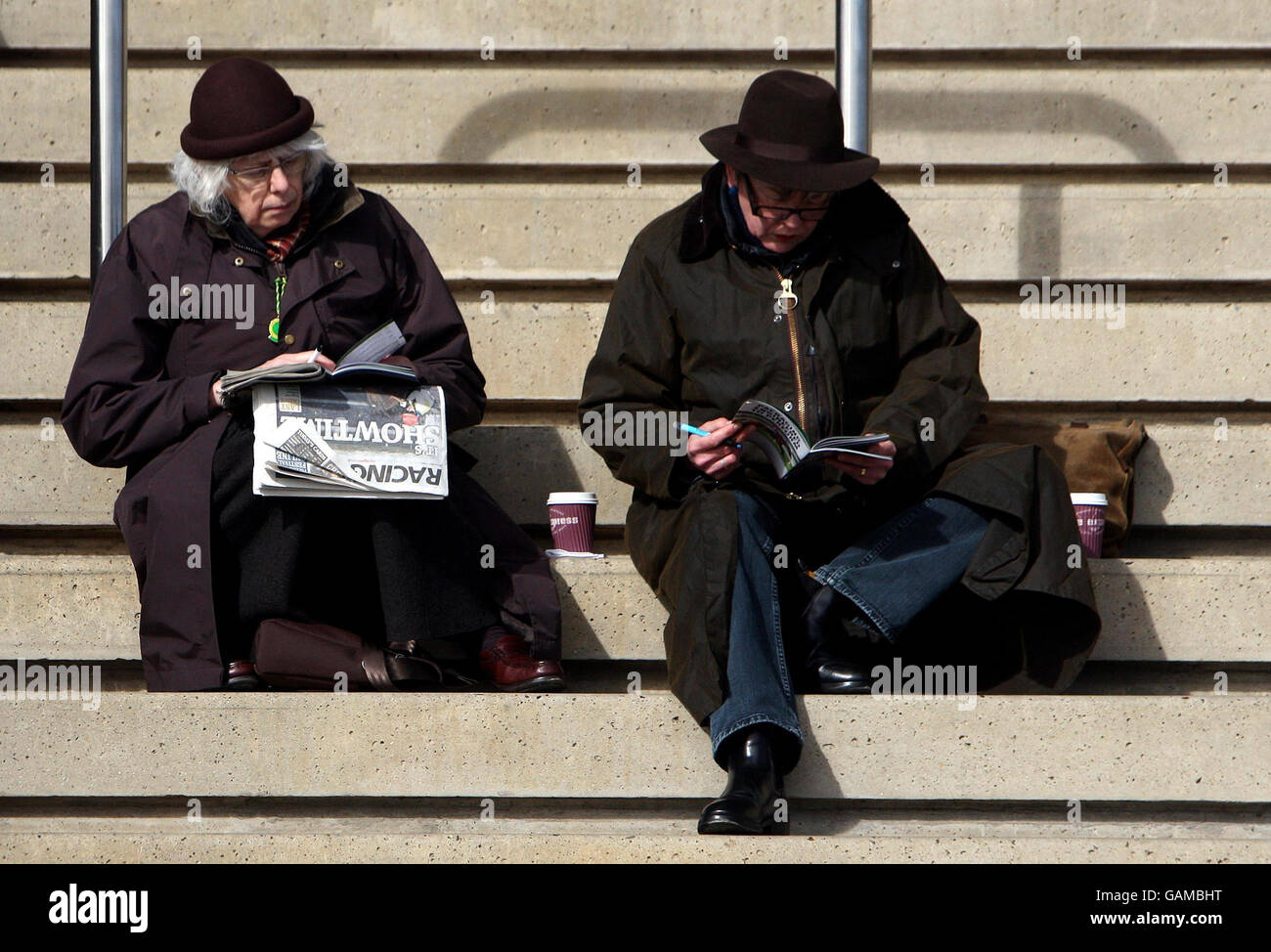 Rennfahrer überprüfen die Zeitungen am ersten Morgen des Cheltenham Festivals auf der Cheltenham Rennbahn. Stockfoto