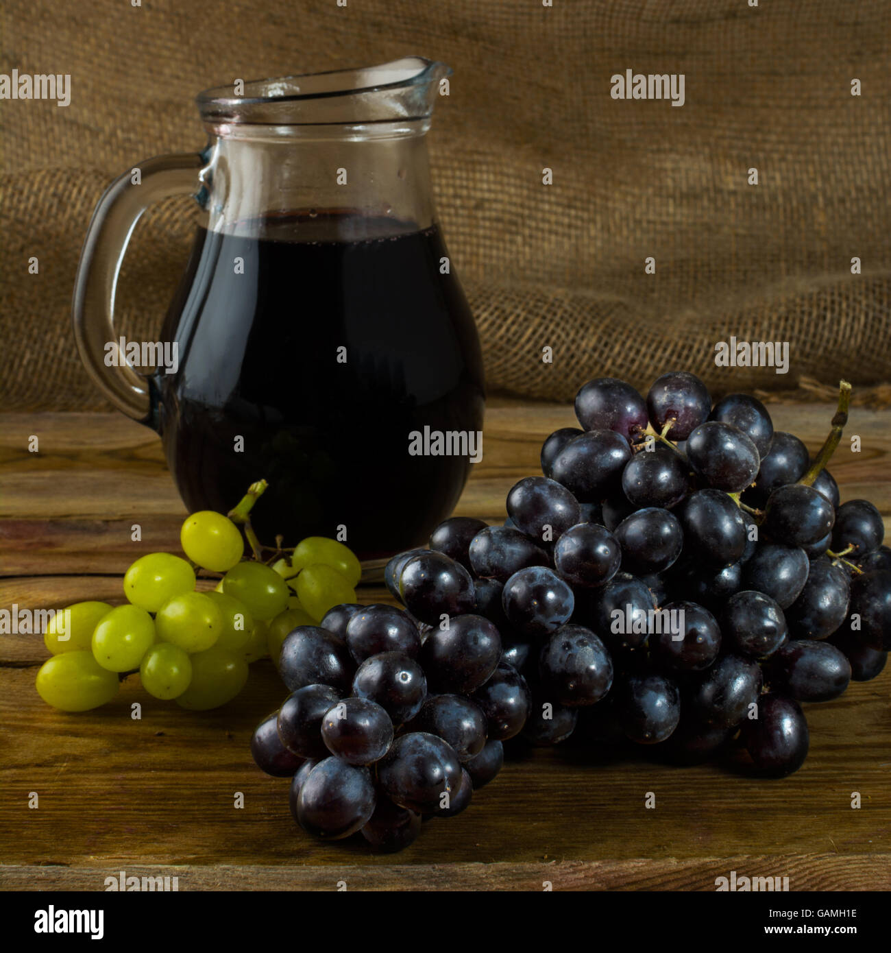 Traube und Wein Krug auf einem dunklen Hintergrund aus Holz. Haufen von Trauben. Cluster-Trauben.  Bündel Weintrauben. Trauben. Traube. Glas Stockfoto