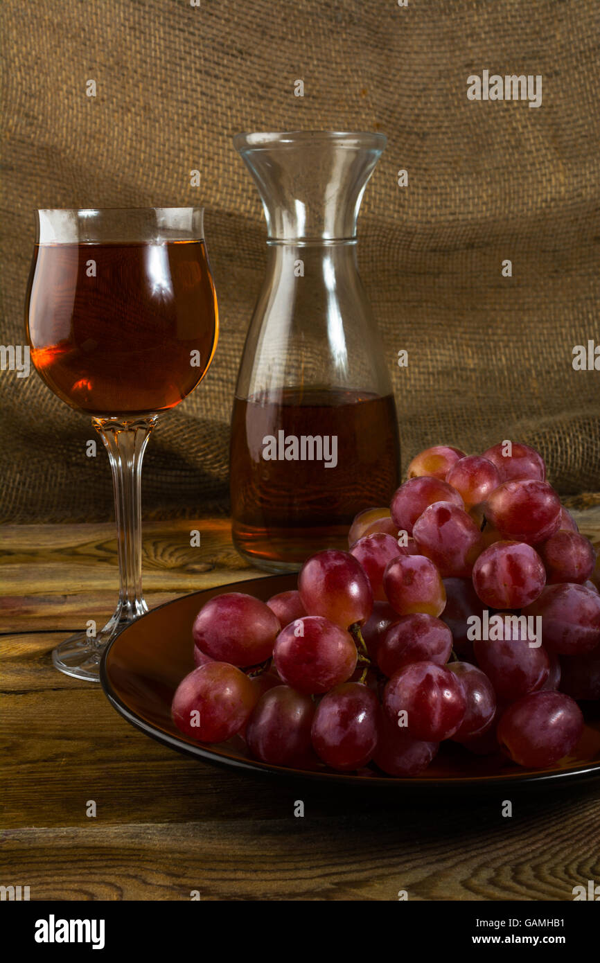 Rote Weintrauben und einem Glas Wein auf einem dunklen Hintergrund aus Holz. Cluster von Trauben. Haufen von Trauben. Cluster-Trauben.  Haufen Stockfoto