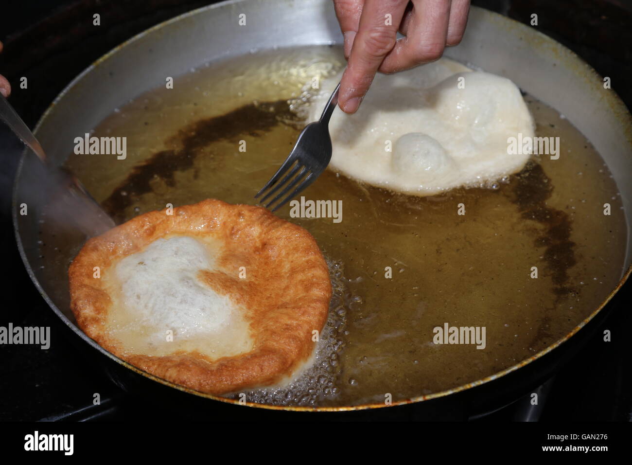 zwei große Pfannkuchen in heißem Öl in einen Aluminium-Topf getaucht Stockfoto