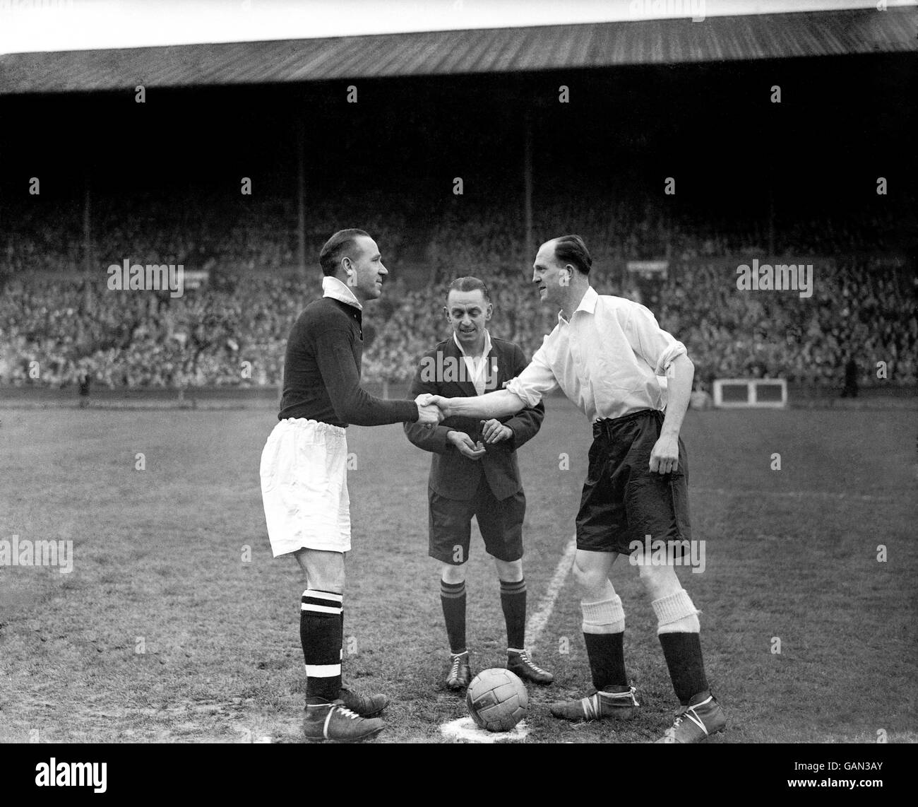 Zweiter Weltkrieg - Großbritannien und Commonwealth - Heimatfront - Fußball - Kriegszeit International - England gegen Schottland - Wembley - 1944. Die beiden Kapitäne, der schottische Matt Busby (l) und der englische Stan Cullis (r), schütteln sich vor dem Spiel die Hände, beobachtet von Schiedsrichter WE Wood (c) Stockfoto