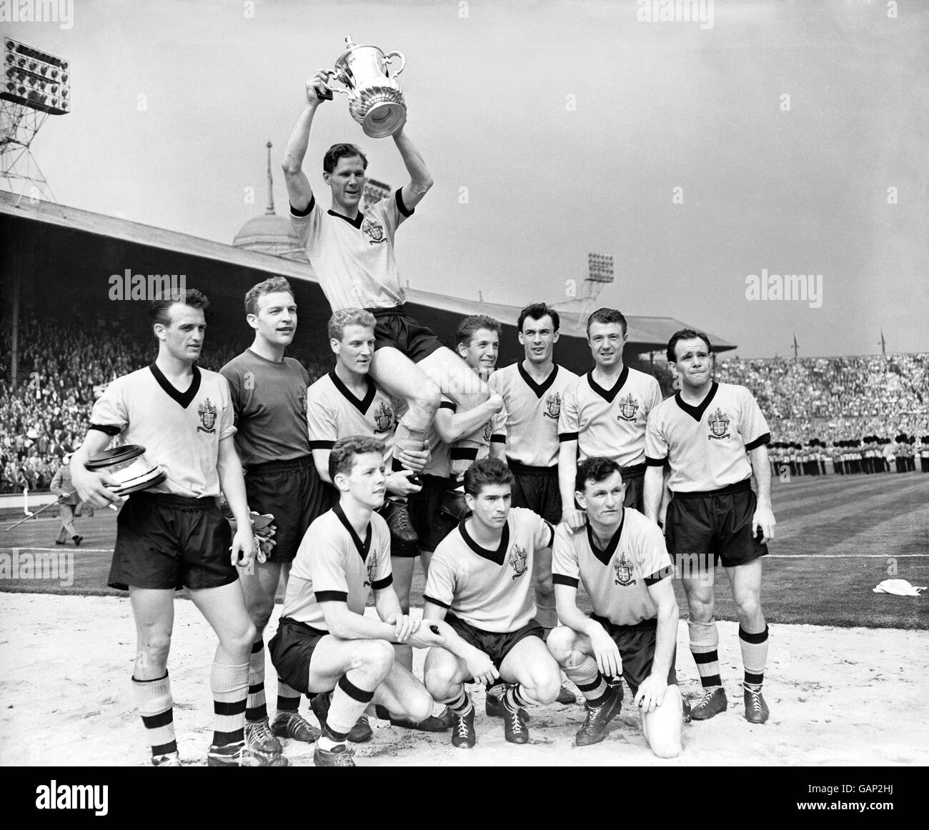 Wolverhampton Wanderers Kapitän Bill Slater hält den FA Cup hoch, während er von seinen jubelten Teamkollegen geleitet wird: (Hintere Reihe, l-r) Gerry Harris, Malcolm Finlayson, Ron Flowers, Peter Broadbent, Eddie Clamp, George Showell und Norman Deeley. (Erste Reihe, l-r) Barry Stobart, des Horne und Jimmy Murray. Stockfoto