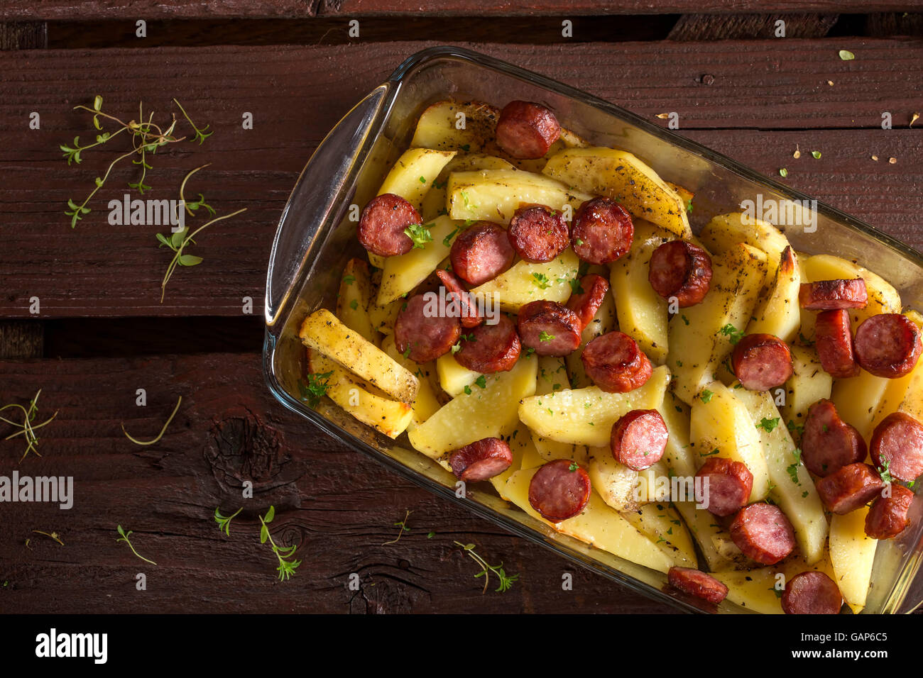 Tablett mit Bratkartoffeln mit Würstchen und Gewürzen auf hölzernen Hintergrund Stockfoto