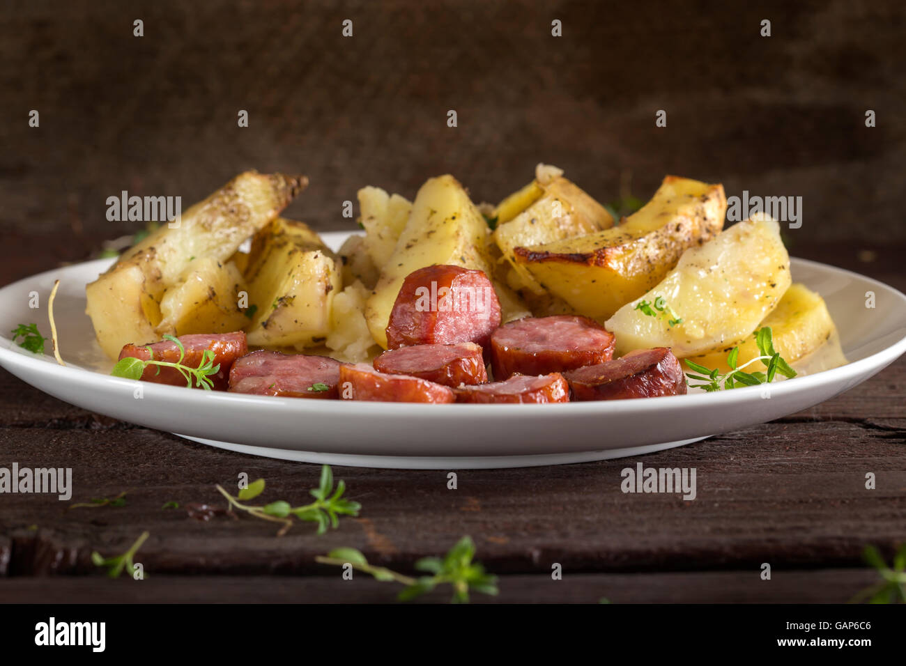 Teller mit Bratkartoffeln mit Würstchen und Gewürzen auf hölzernen Hintergrund Stockfoto