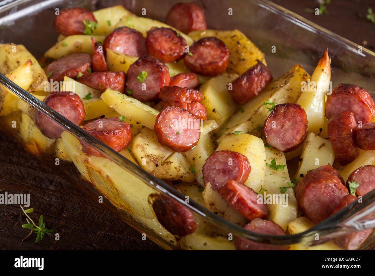 Tablett mit Bratkartoffeln mit Würstchen und Gewürzen auf hölzernen Hintergrund Stockfoto