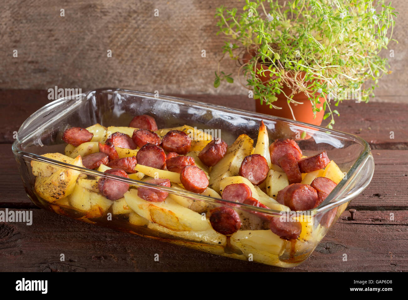 Tablett mit Bratkartoffeln mit Würstchen und Gewürzen auf hölzernen Hintergrund Stockfoto