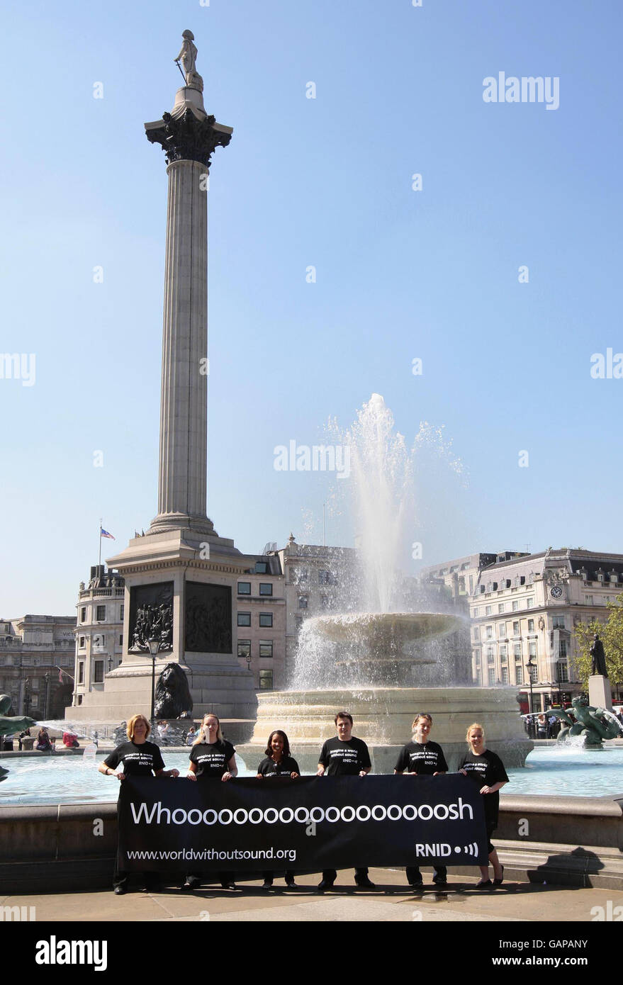 Aktivisten halten ein Banner mit der Untertitelung des „Whoosh“ des Brunnens, um die „Deaf Awareness Week“ zu markieren, indem sie die wichtigsten Wahrzeichen Trafalgar Square, London, untertiteln. Stockfoto