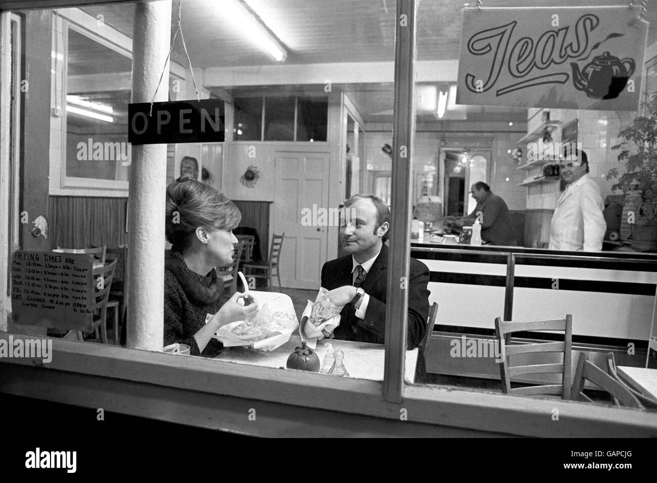 Popstar Phil Collins kauft der Schauspielerin Julie Walters am ersten Drehtag in Buster, einem Film über den größten „Take-away“ der 1960er Jahre, den „Great Train Raub“, ein altmodisches Essen zum Mitnehmen mit Fisch und Chips in einem Café im Süden Londons. Stockfoto