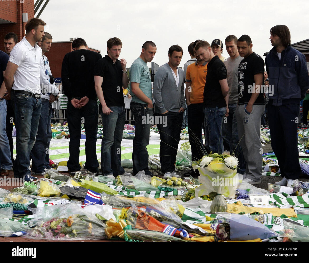 Celtic Spieler schauen Blumen an, nachdem Tribute für Tommy Burns im Celtic Park in Glasgow hinterlassen wurden. Stockfoto